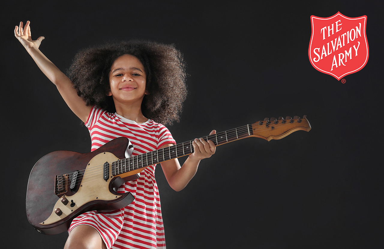 Girl holding a guitar on a dark background -image for the client portfolio page linking to The Salvation Army Project